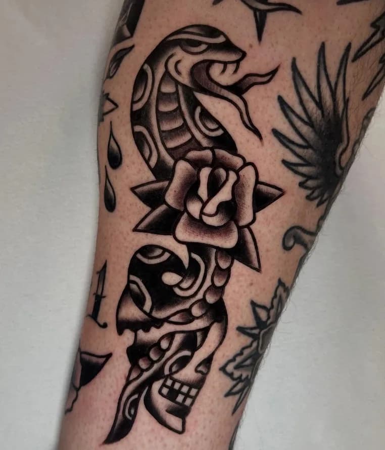 Black and grey traditional cobra snake tattoo with a rose and a skull, on the forearm