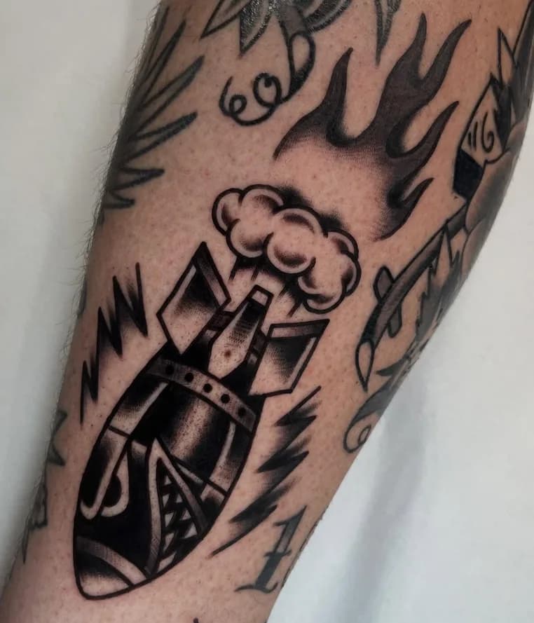 Black traditional bomb tattoo with smoke, part of a forearm sleeve