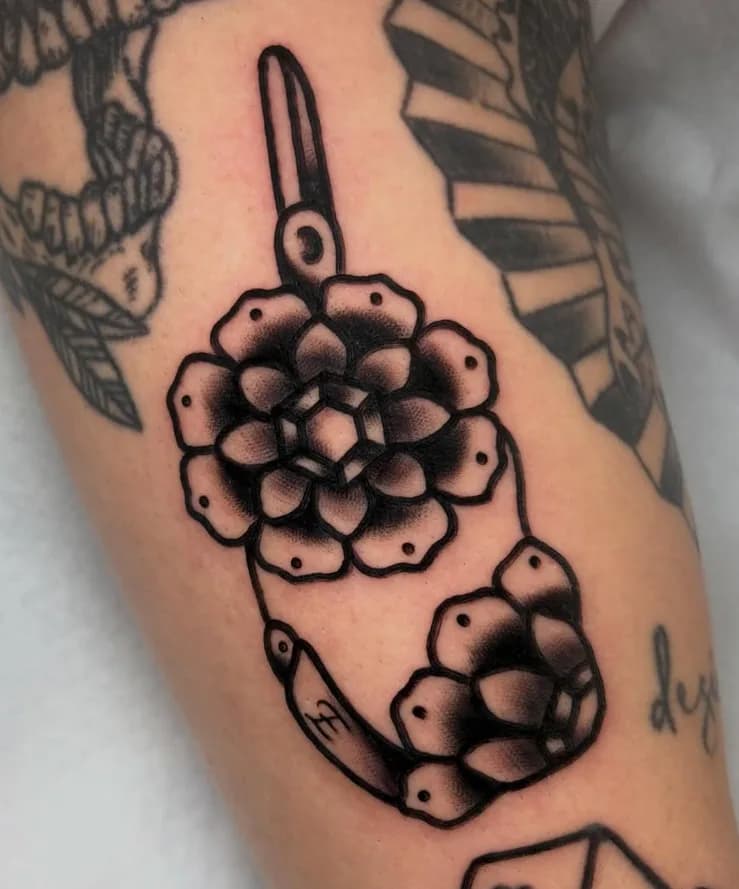 Black traditional flower tattoo, part of a forearm sleeve