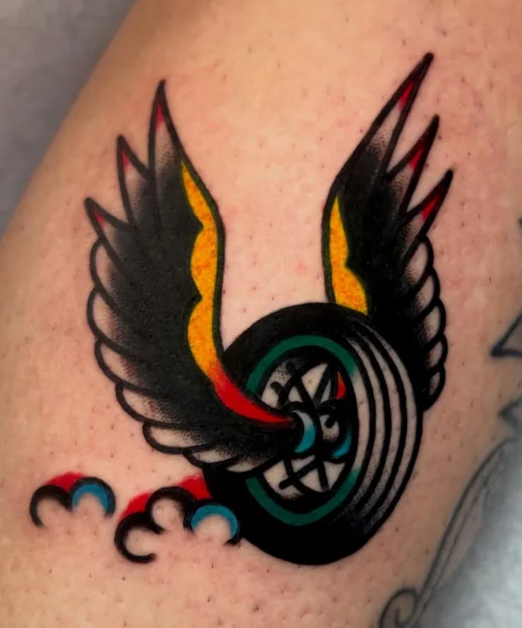 Traditional colorful winged wheel tattoo, on the leg