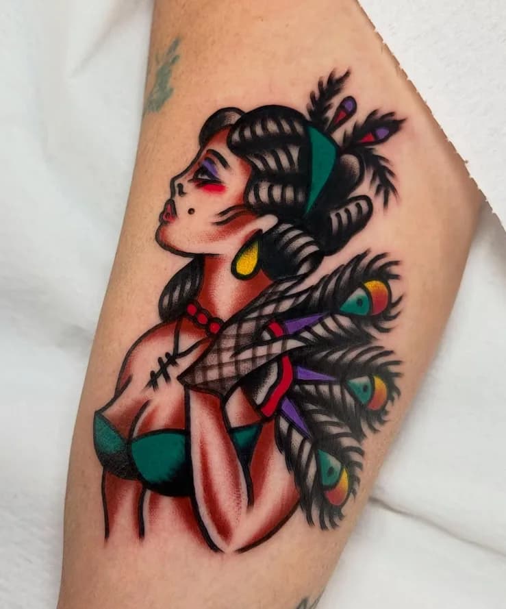 Traditional colorful pin-up woman with peacock feathers tattoo, on the forearm